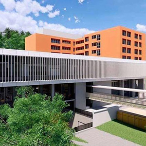 Ein mehrstöckiges, orangenes Gebäude im Hintergrund und im Vordergrund ein moderner, langgezogener Abschnitt mit futuristischen Fenstern.